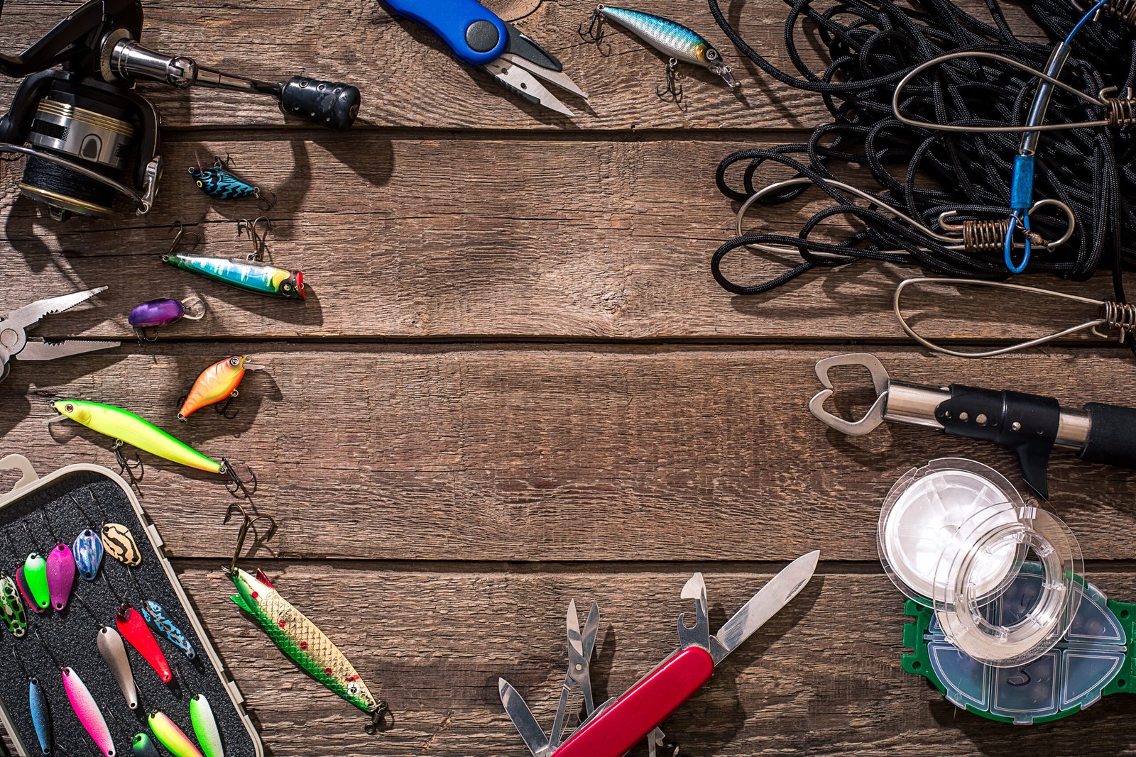 Fishing tackle - fishing spinning, fishing line, hooks and lures on wooden background.